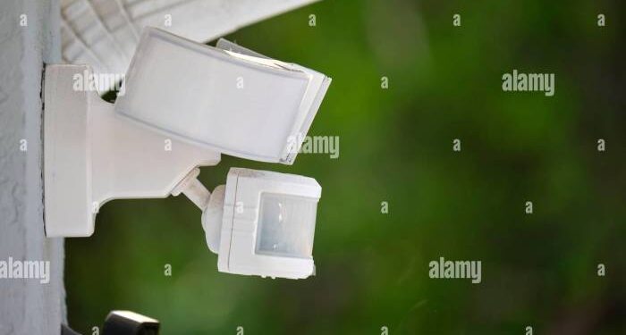 Motion sensor with light detector mounted on exterior wall of private ...